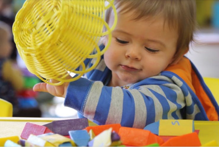 Child playing with a yellow toy and colorful blocks
