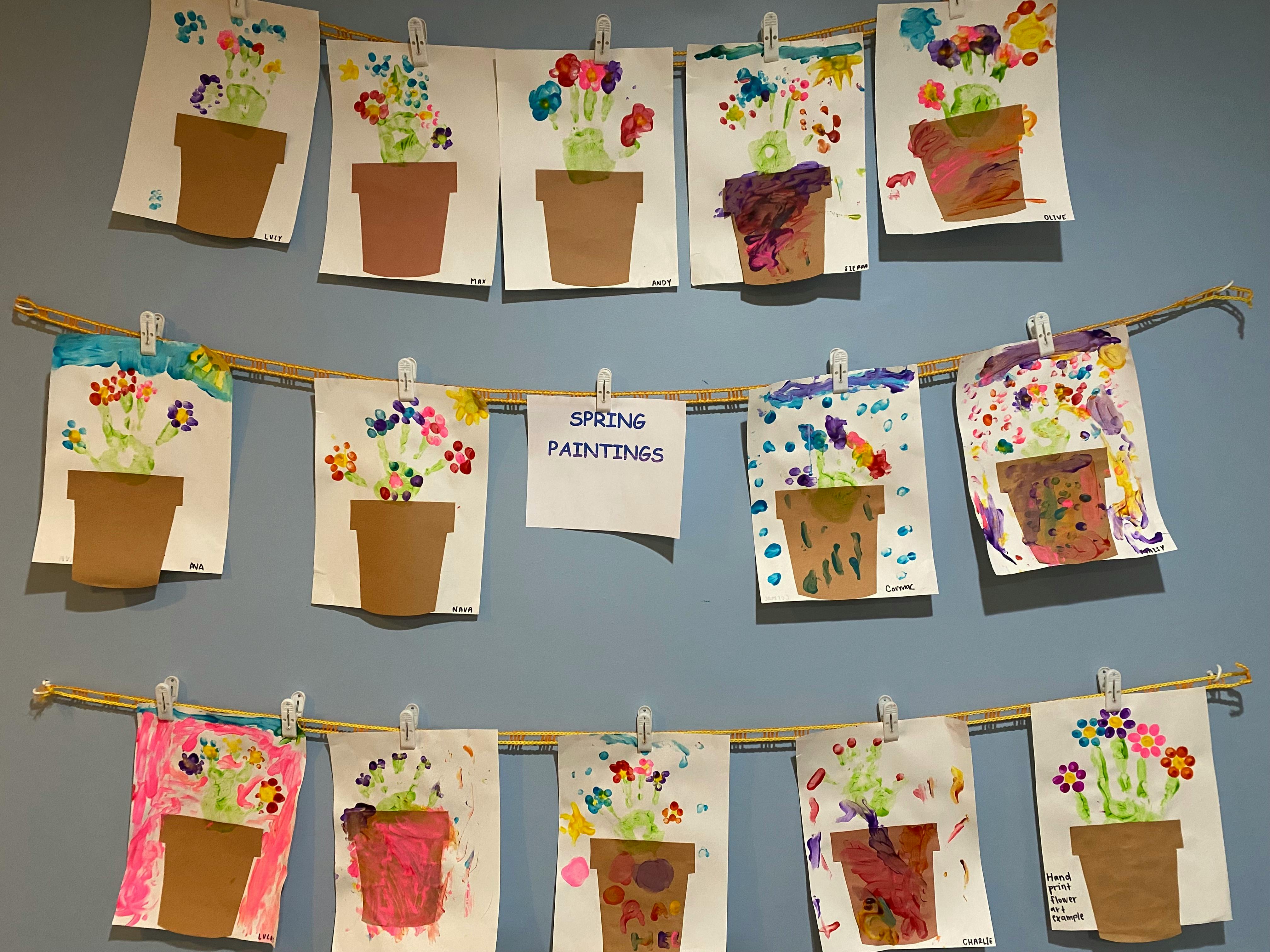 Children's artwork of potted flowers displayed on a wall