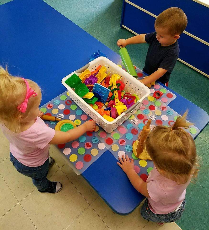 Three children playing with toys at a table