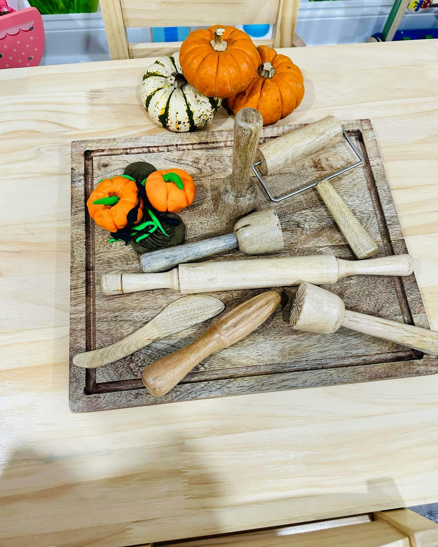 Miniature pumpkins and wooden kitchen tools on a cutting board