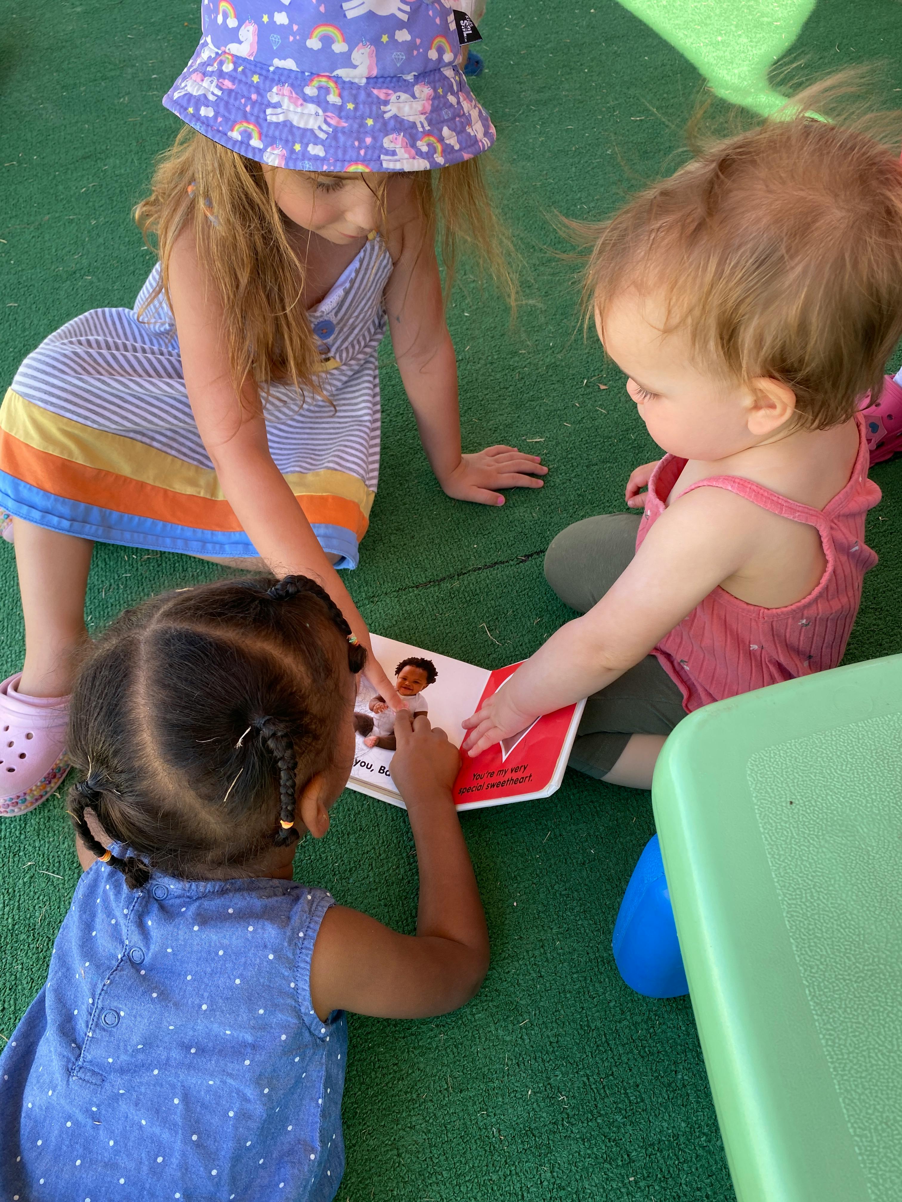 Three children on the floor looking at a book together