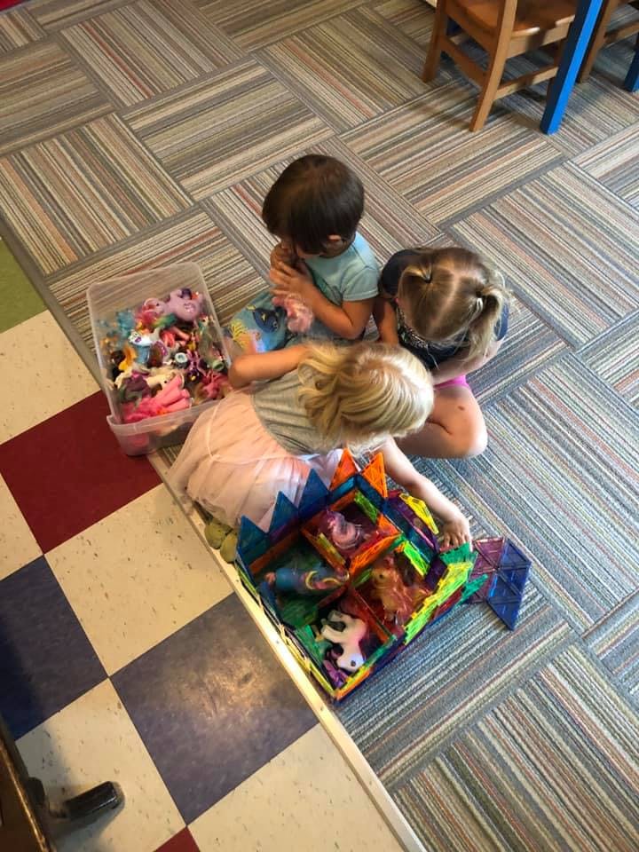 Three children playing with toys on the floor