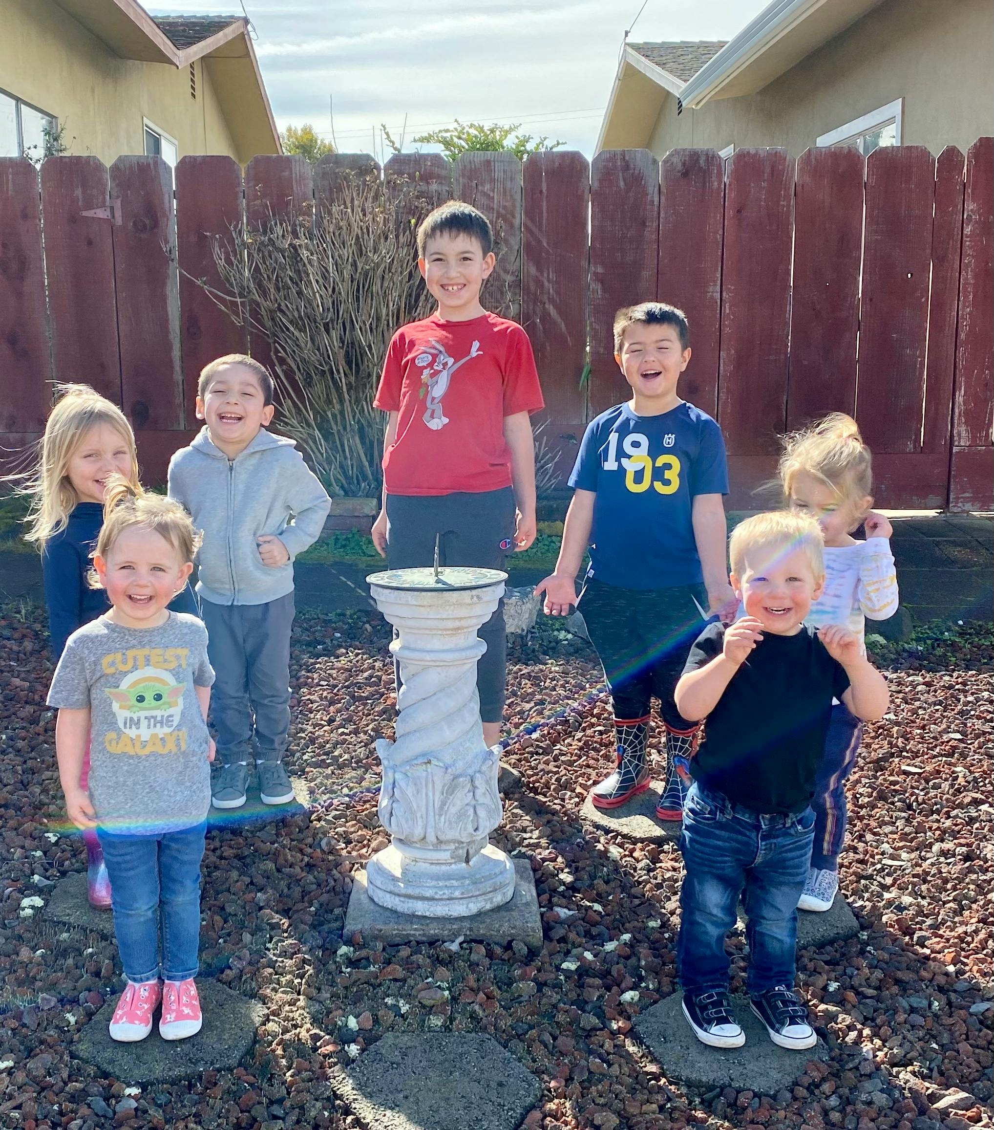 Group of children standing around a sundial outdoors