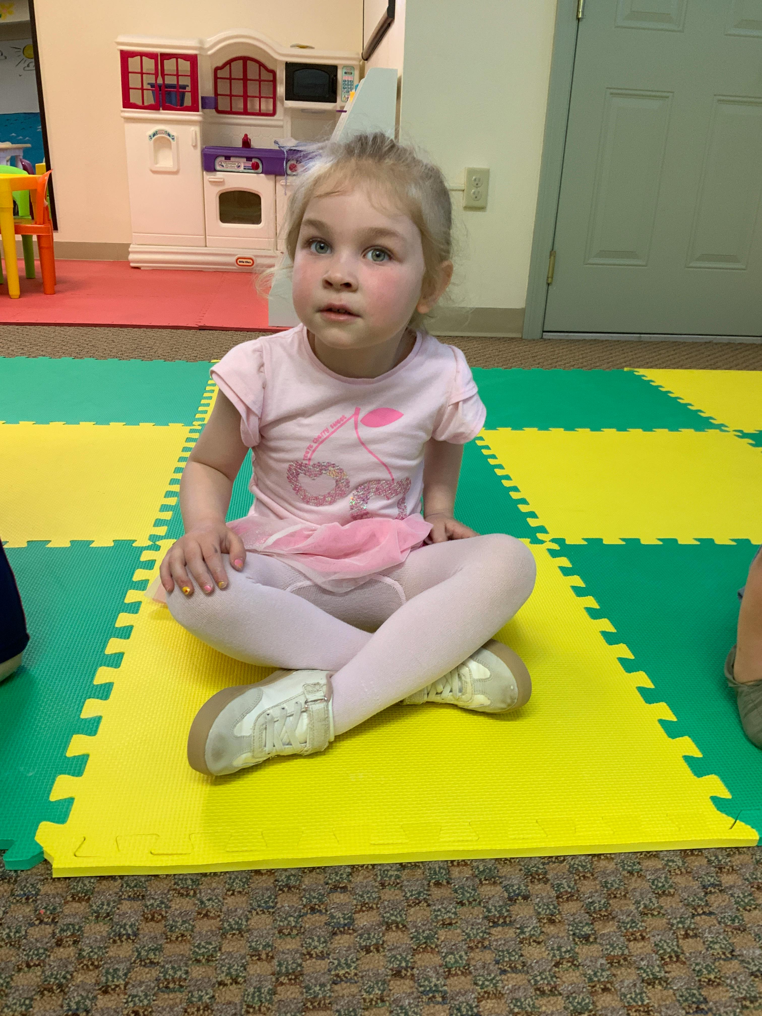 Child lying on interlocking foam mat in a classroom