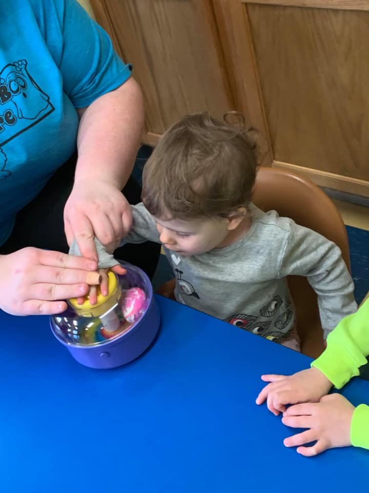 Adult and child playing with a toy on a blue table