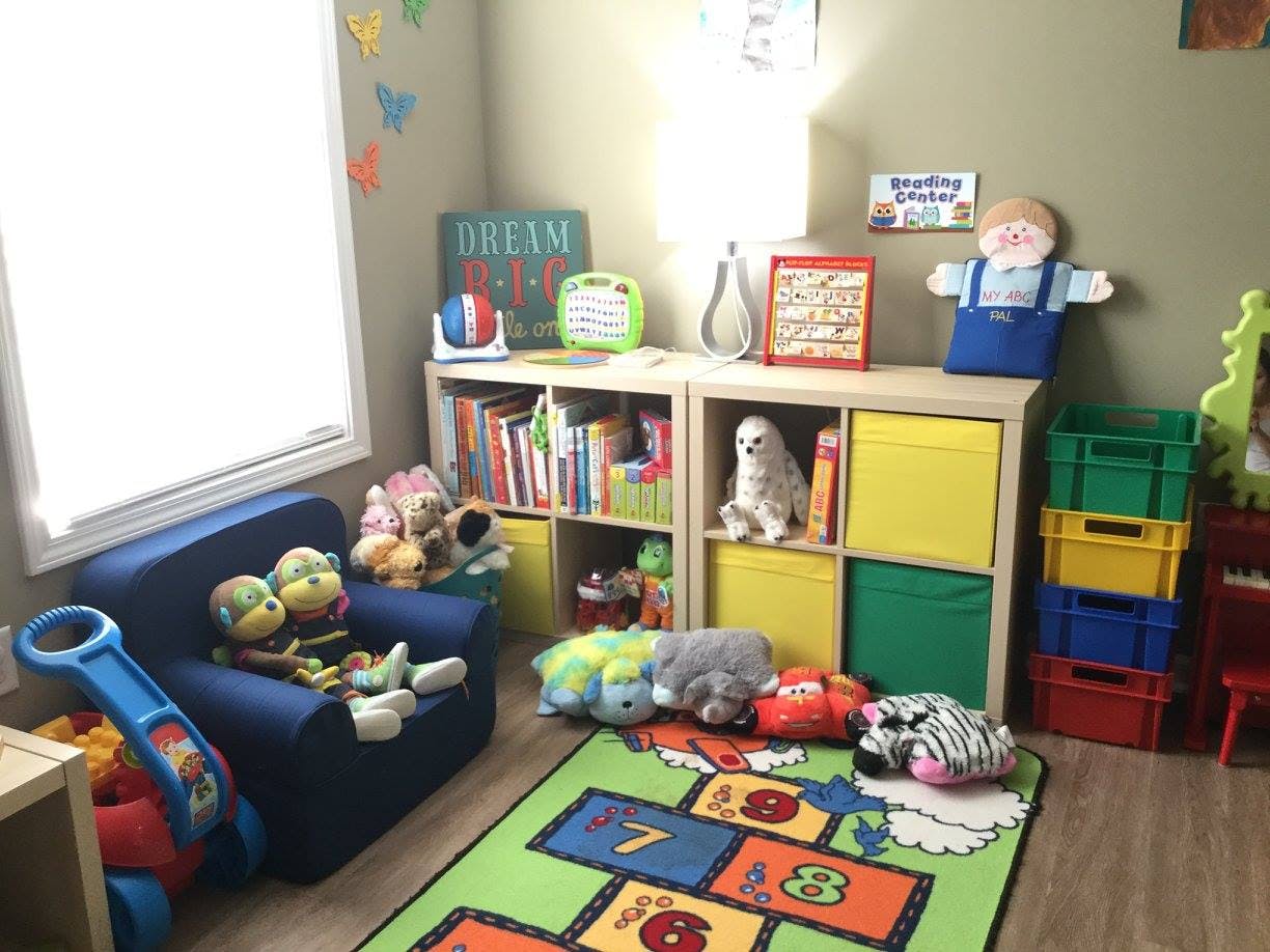 Playroom with a blue chair, bookshelves, toys, and a hopscotch rug