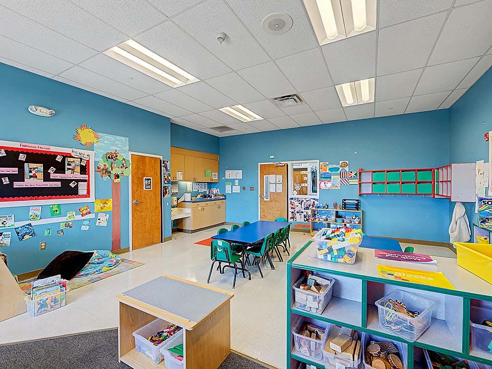 Classroom with blue walls, tables, chairs, and learning materials