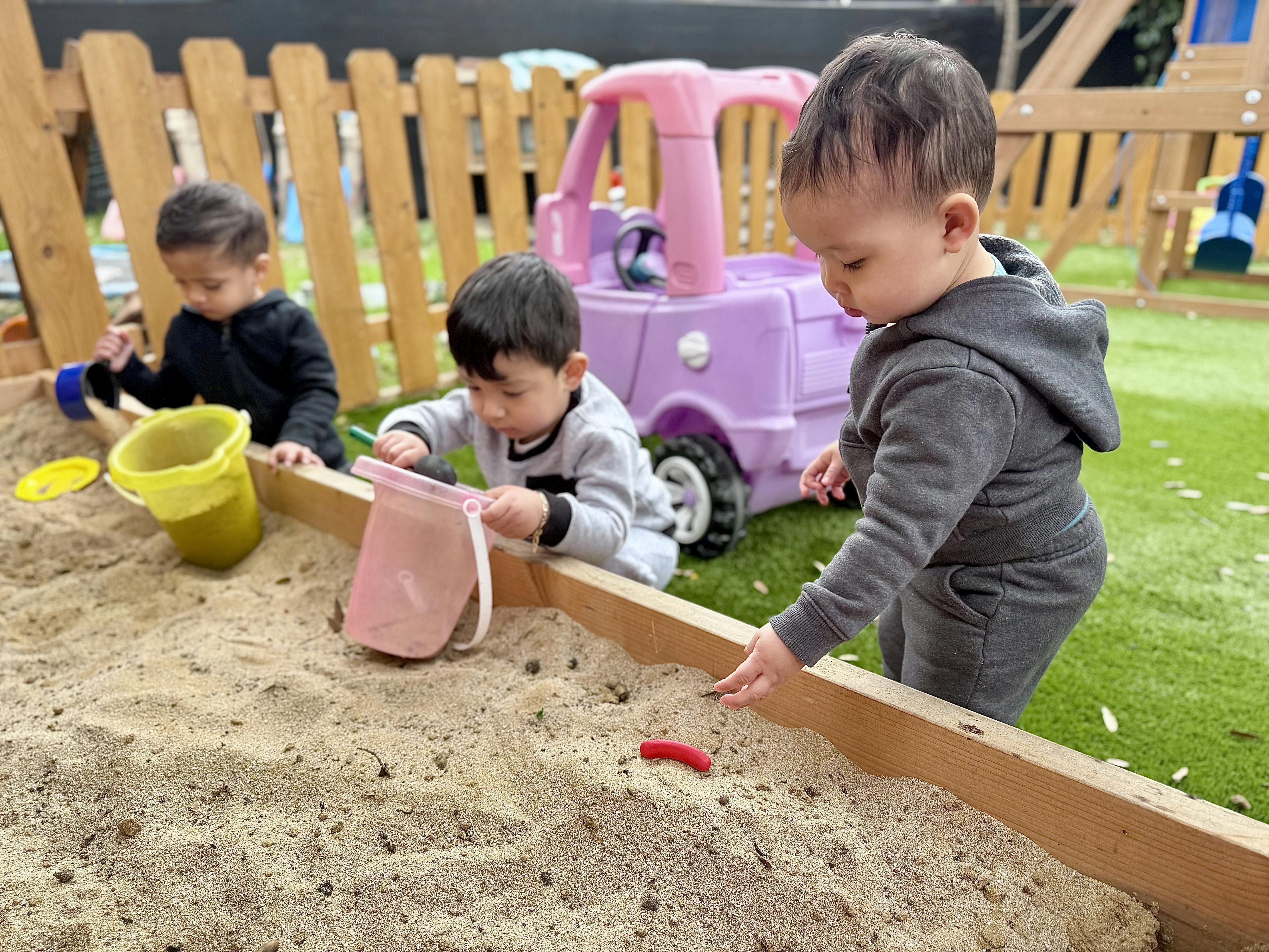 Three children playing in a sandbox