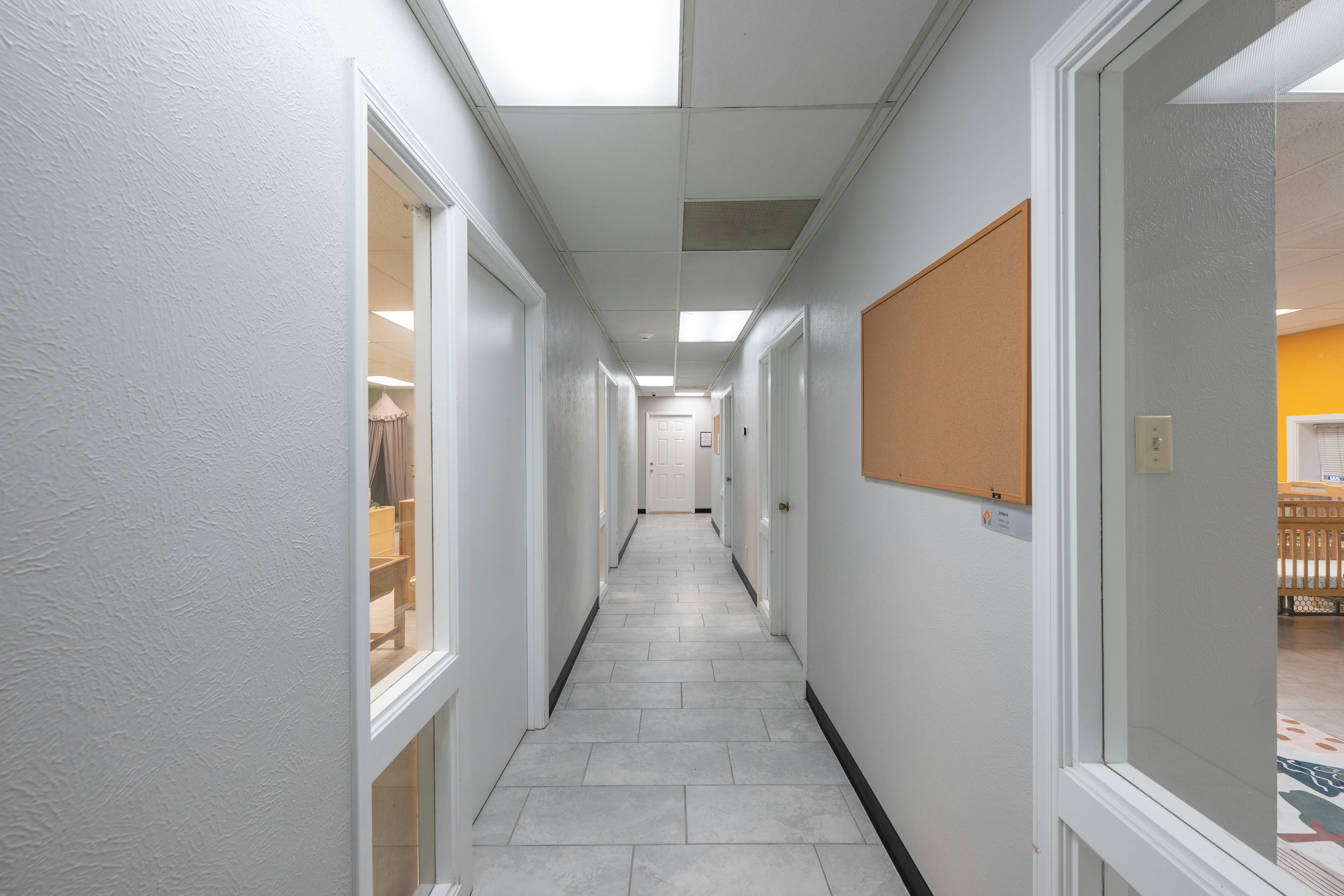 Long hallway with multiple doors and a cork board on the wall