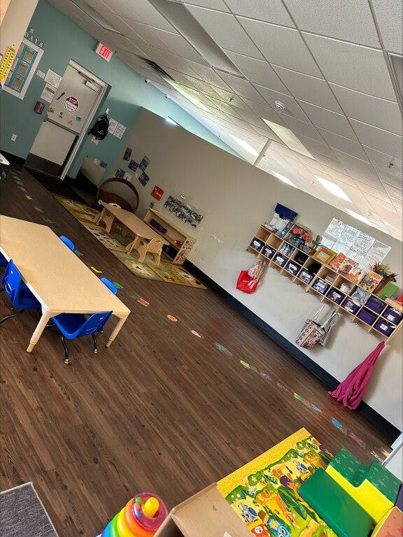 Classroom with small tables and chairs, storage cubbies, and play mats