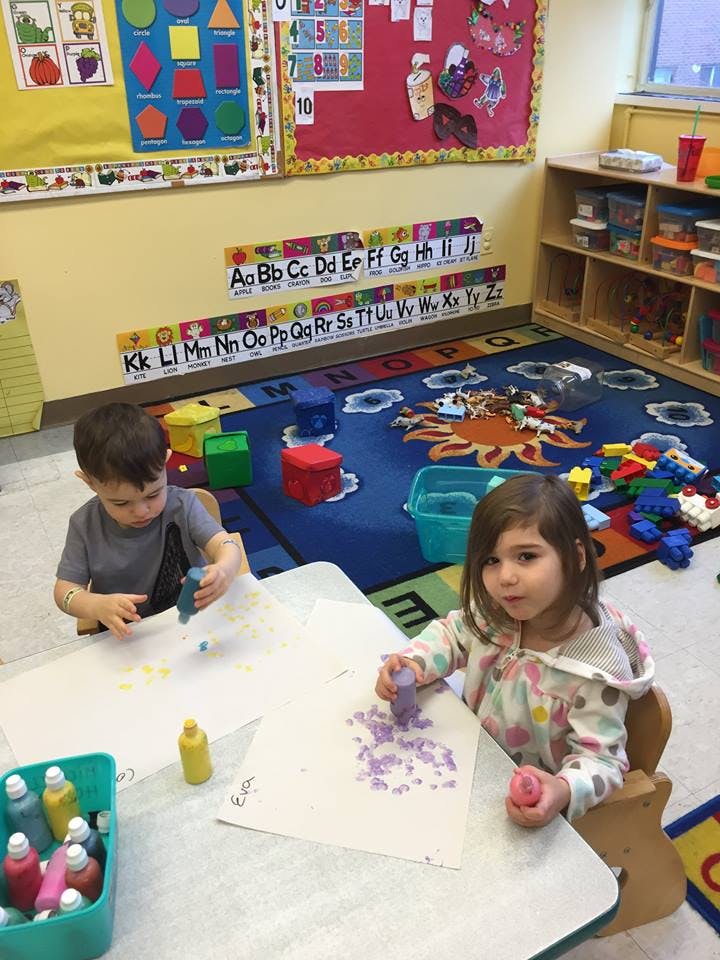 Two children painting at a table in a classroom
