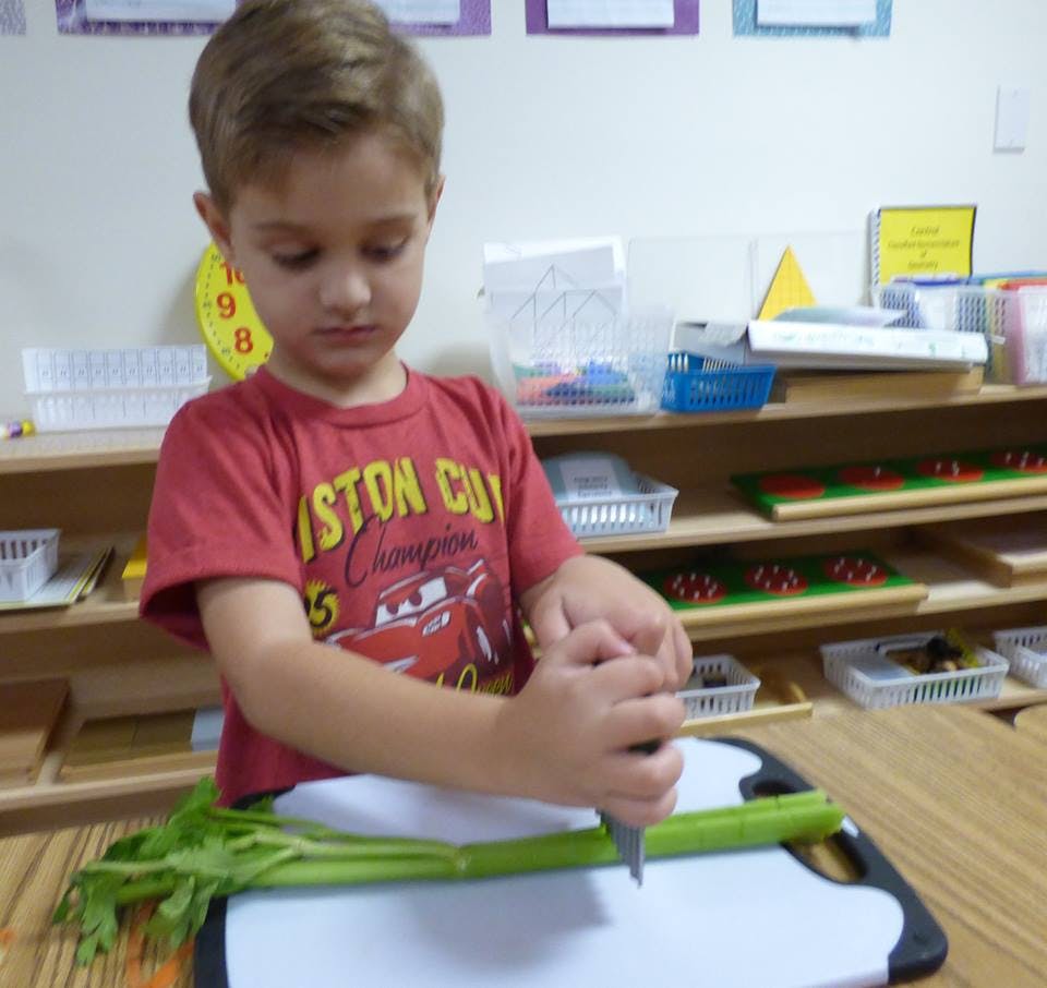 Child cutting celery on a cutting board