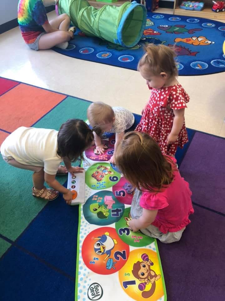 Children playing with a numbered mat on the floor in a classroom