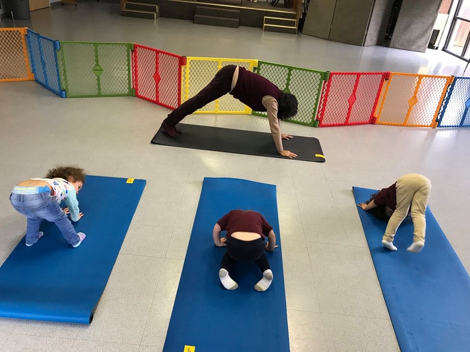 Person and two children doing yoga poses on mats