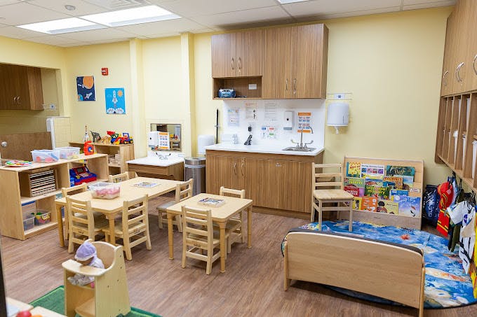 Classroom with child-sized tables and chairs, play kitchen, and sink area