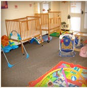 Two empty cribs in a room with baby toys