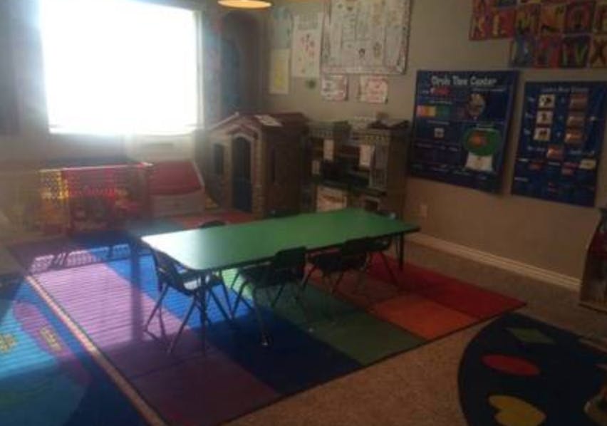 Classroom with a green table, chairs, and colorful rug