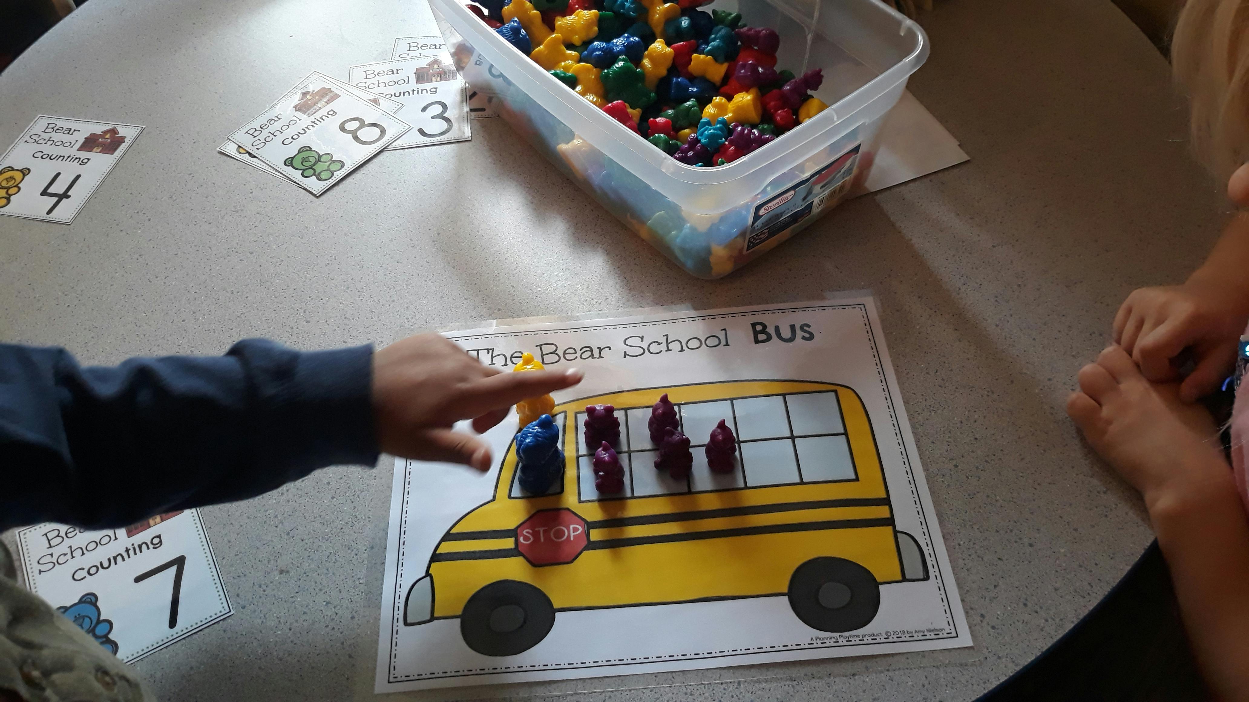 Person pointing at a school bus drawing with small figures on it