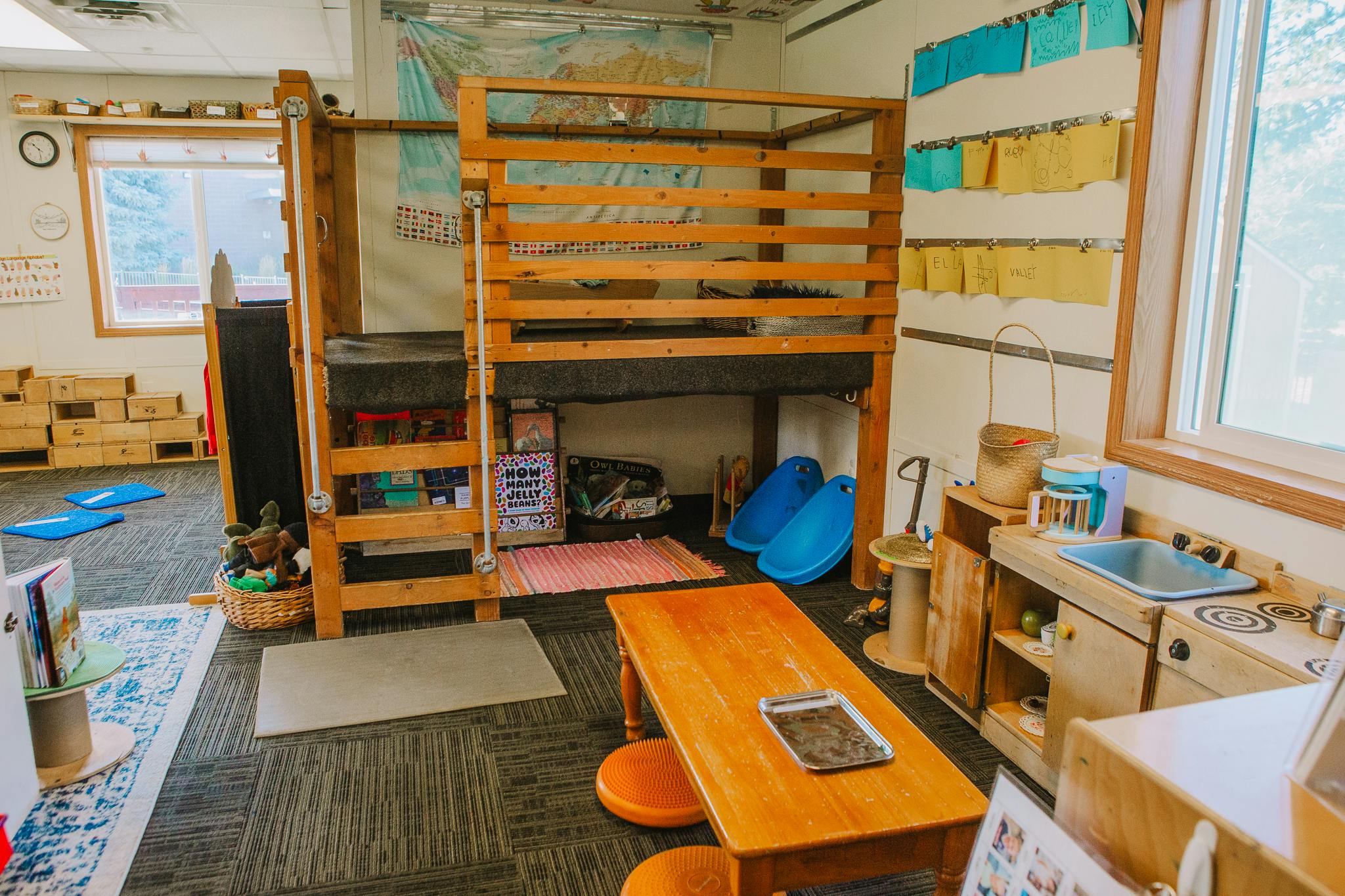Children's play area with a wooden bunk bed, small table, and play kitchen