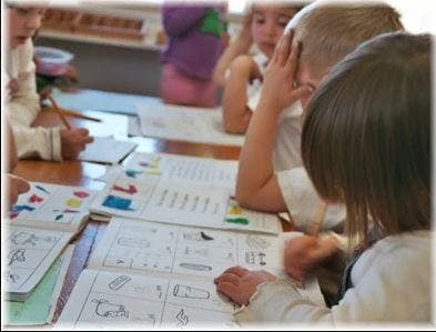 Children sitting at a table with open workbooks