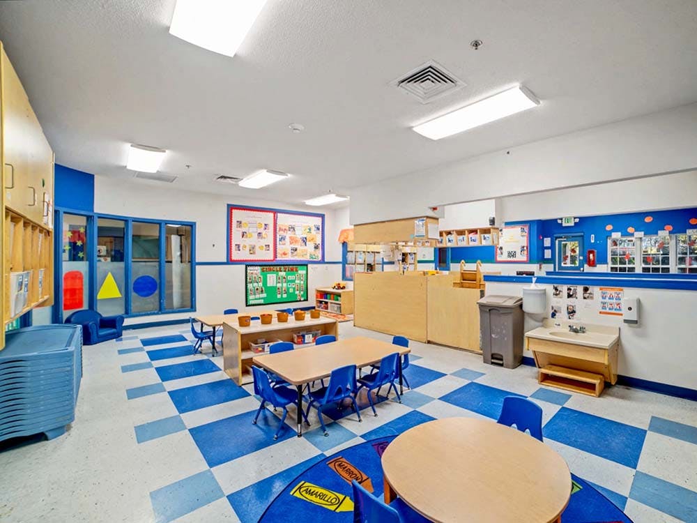 Empty colorful preschool classroom with small tables and chairs