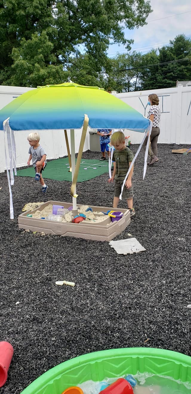 Children playing in a sandbox under an umbrella