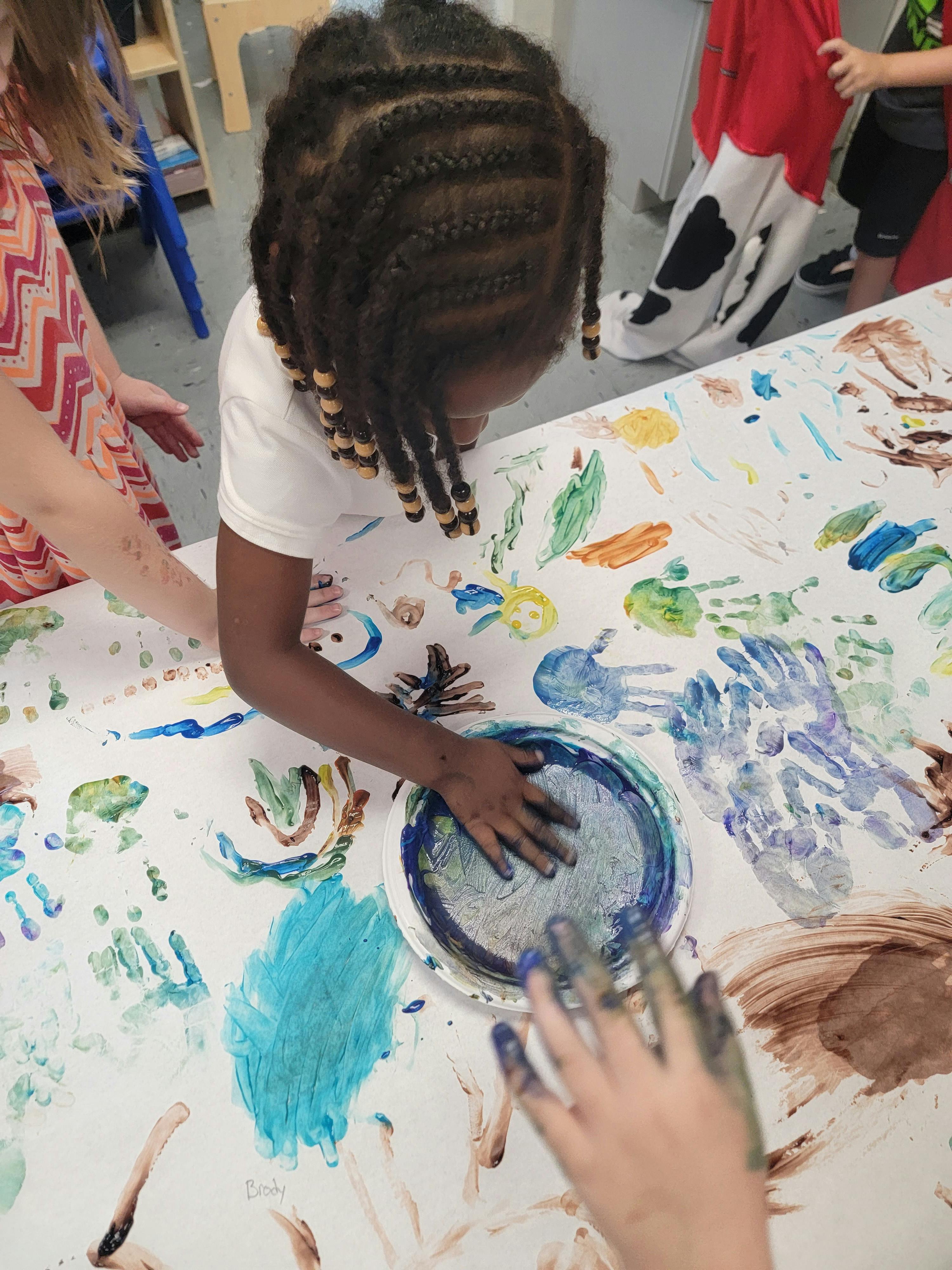 Child with braided hair painting on a large sheet of paper