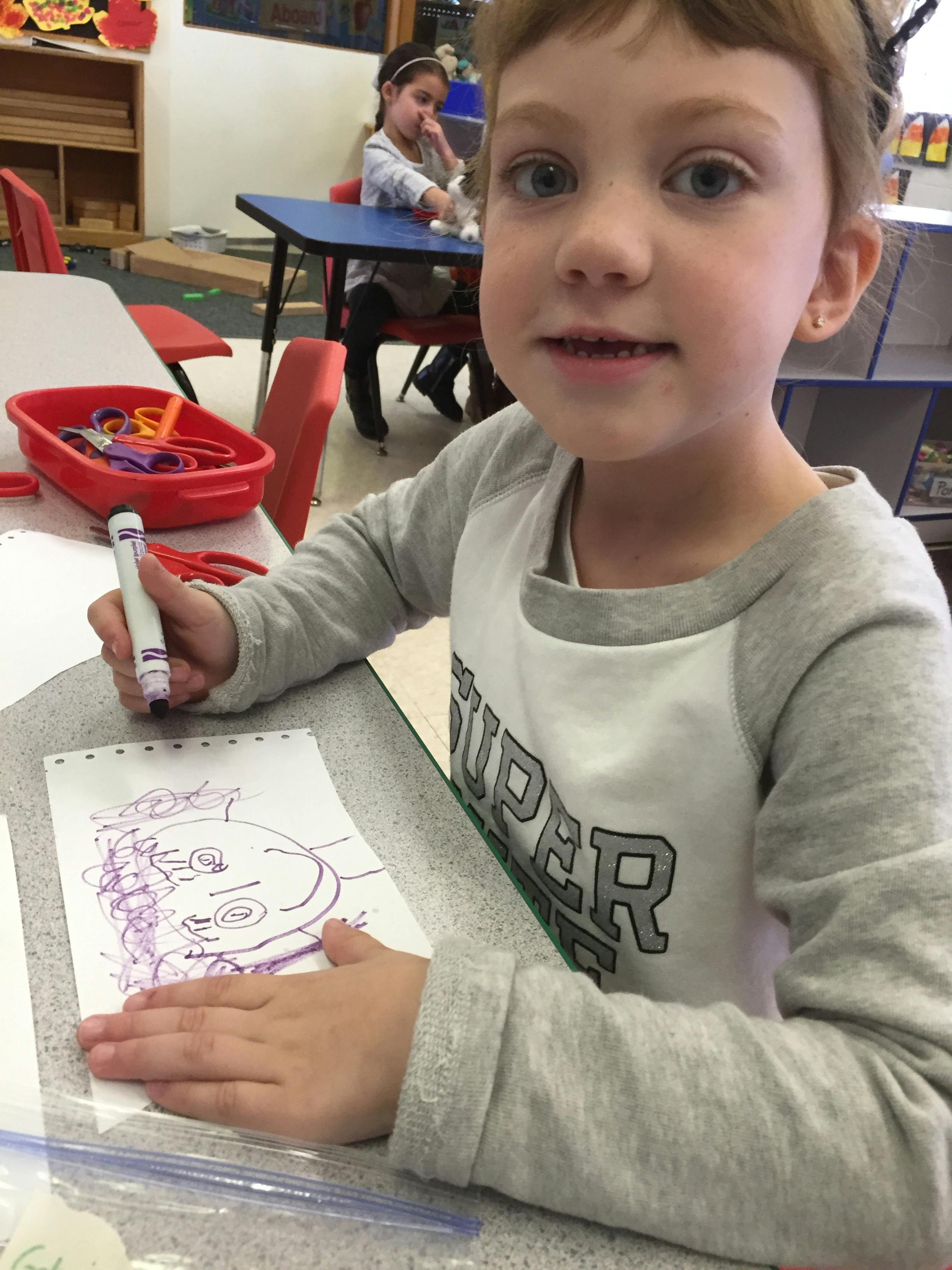 Child drawing with a marker in a classroom