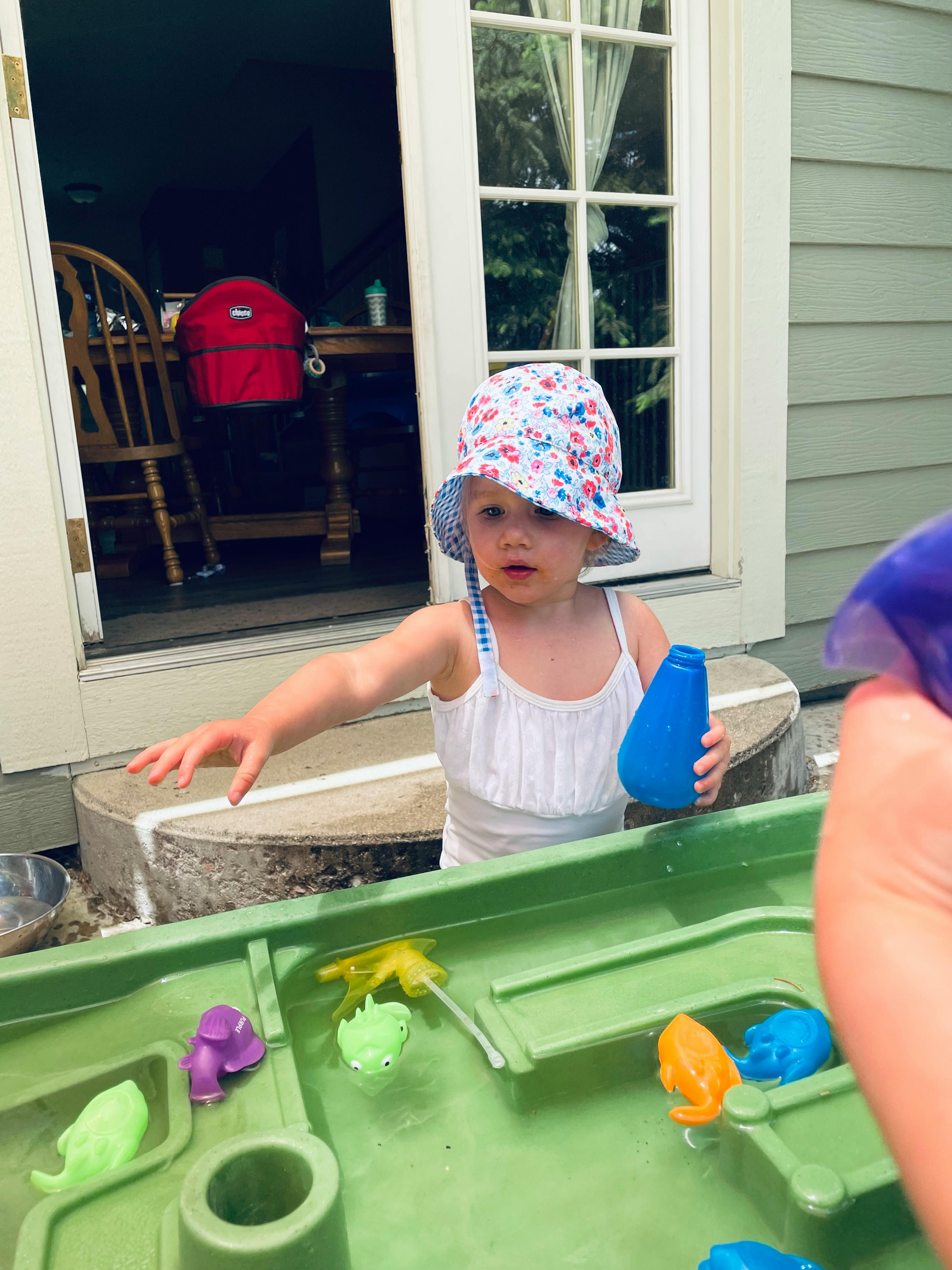 Child in a hat playing with a water table