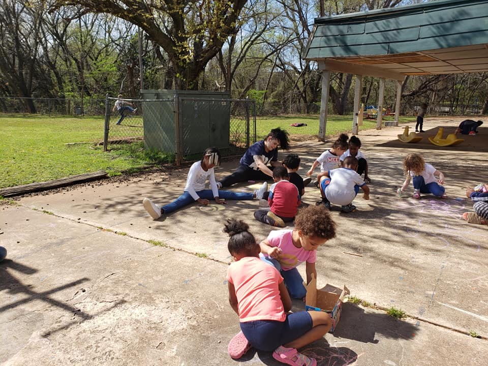 Adults and children sitting on concrete outdoors