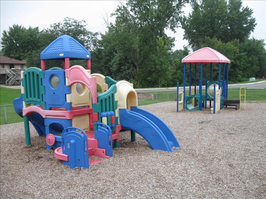 Colorful playground equipment with slides and climbing structures on wood chips
