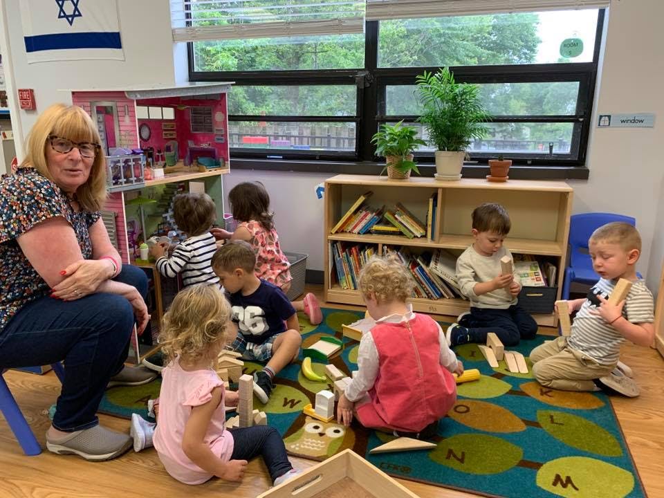 Adult and children playing with toys in a classroom