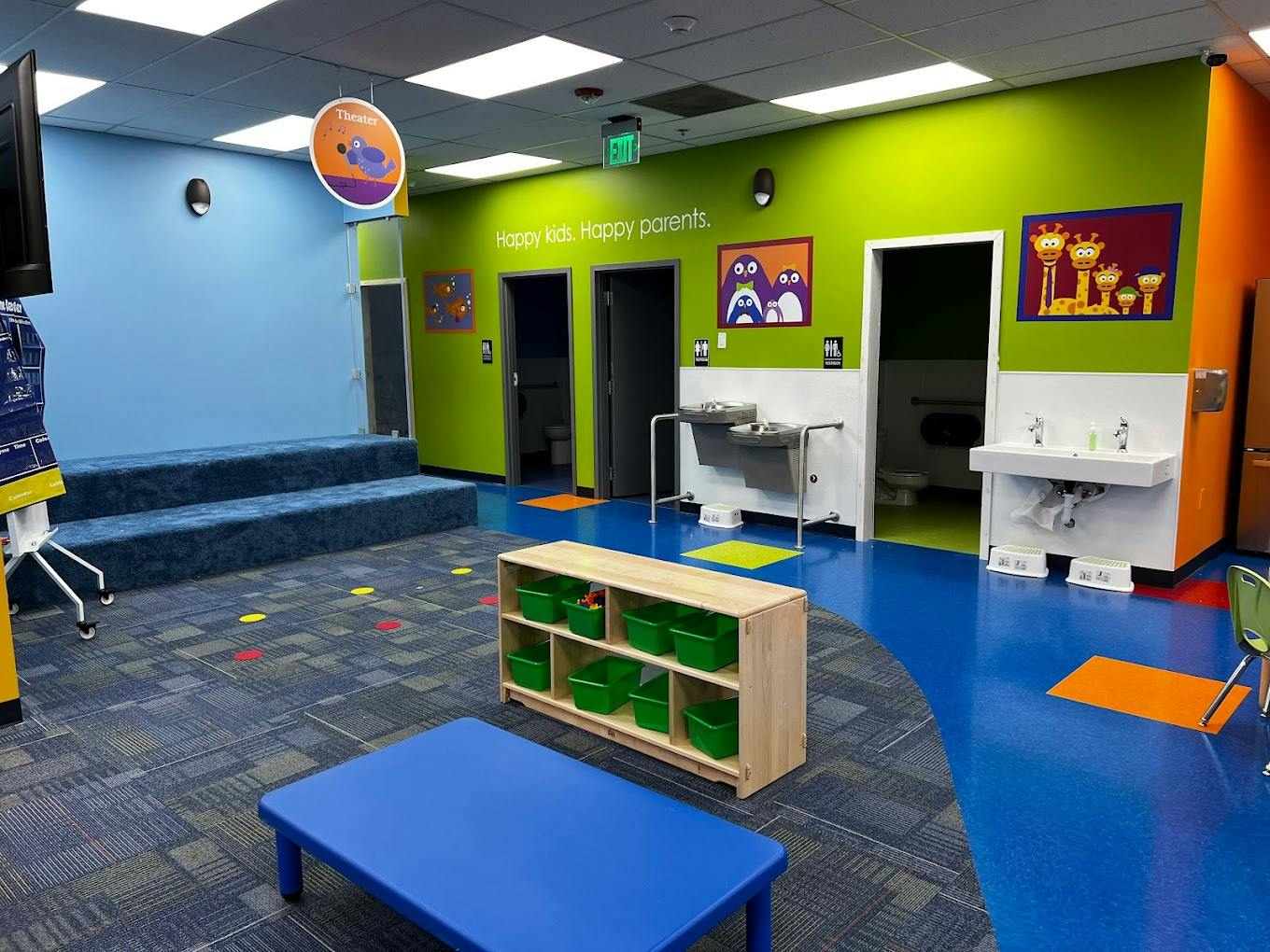 Children's play area with blue and green walls, small tables, and sinks