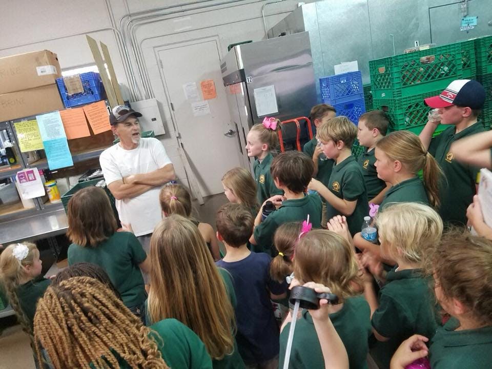 Person speaking to a group of children in a room