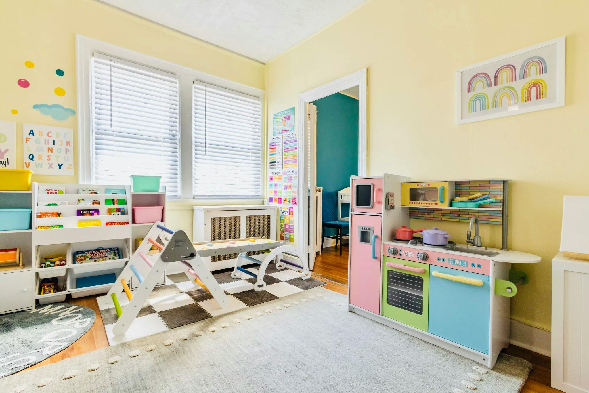 A children's play area with a bookshelf, play kitchen, and climbing toys