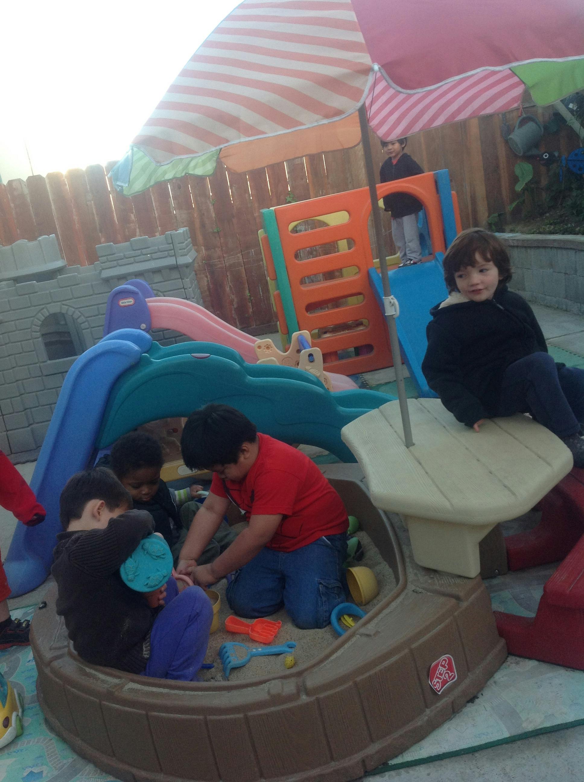 Children playing in a sandbox and on playground equipment