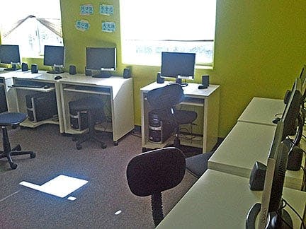 Computer lab with multiple desks, monitors, and chairs