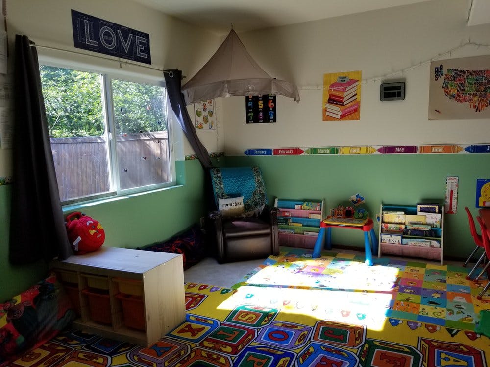 Children's classroom with brightly colored rug, bookshelves, and window