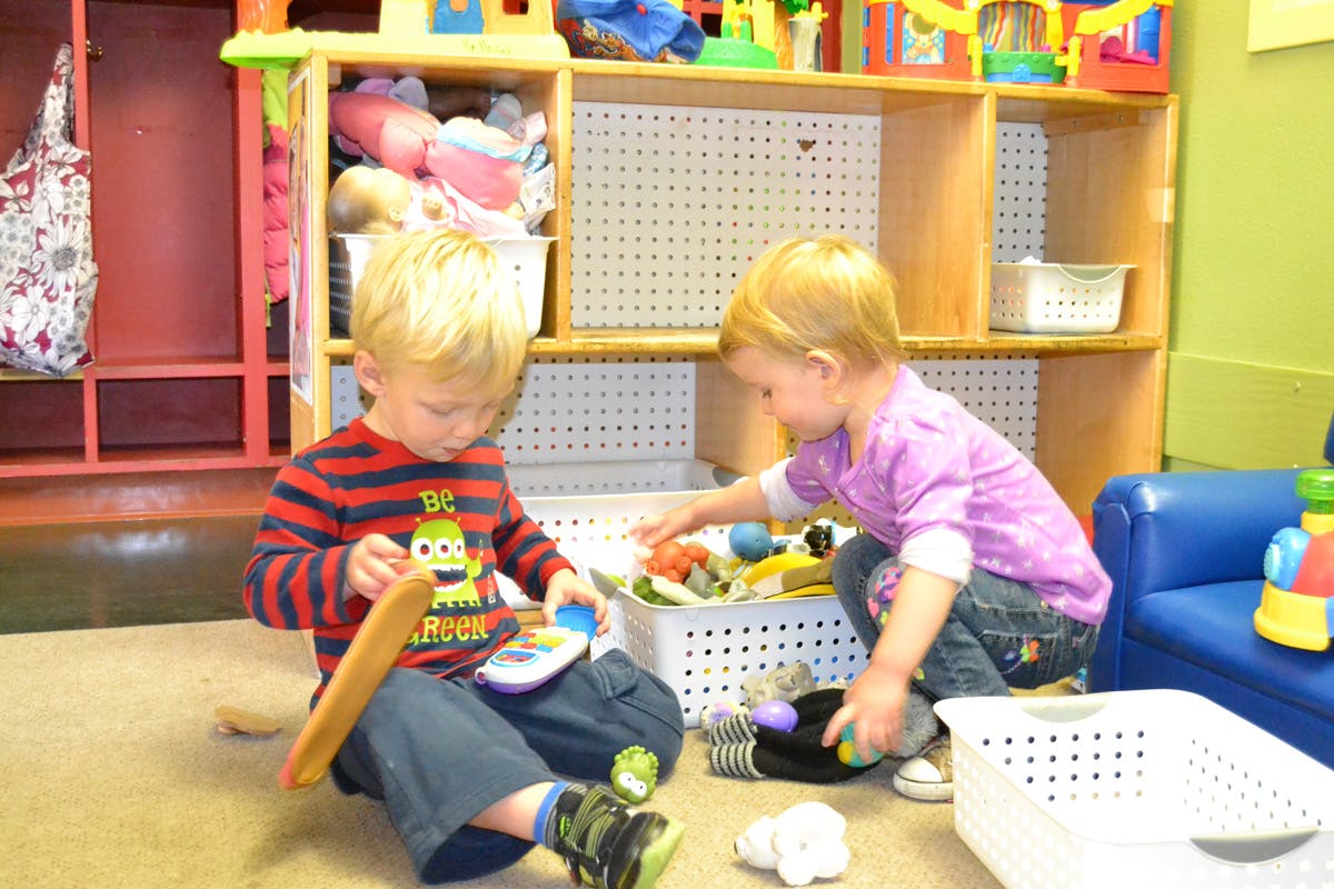 Two children playing with toys on the floor in a classroom