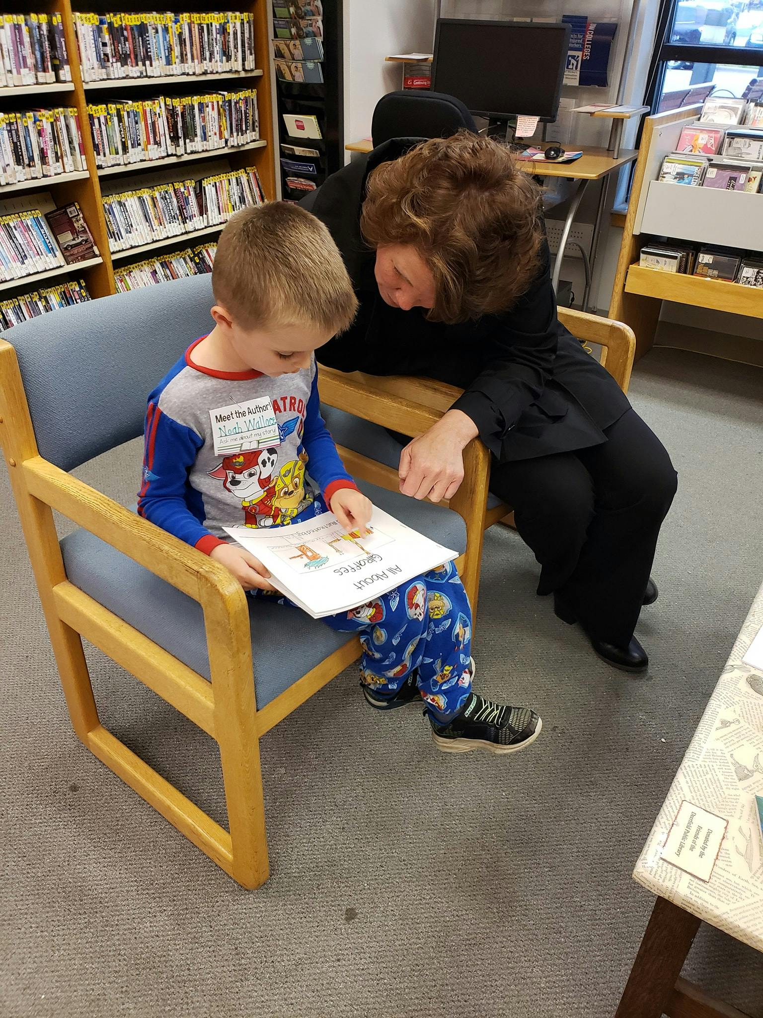 Adult and child reading a book together in a library