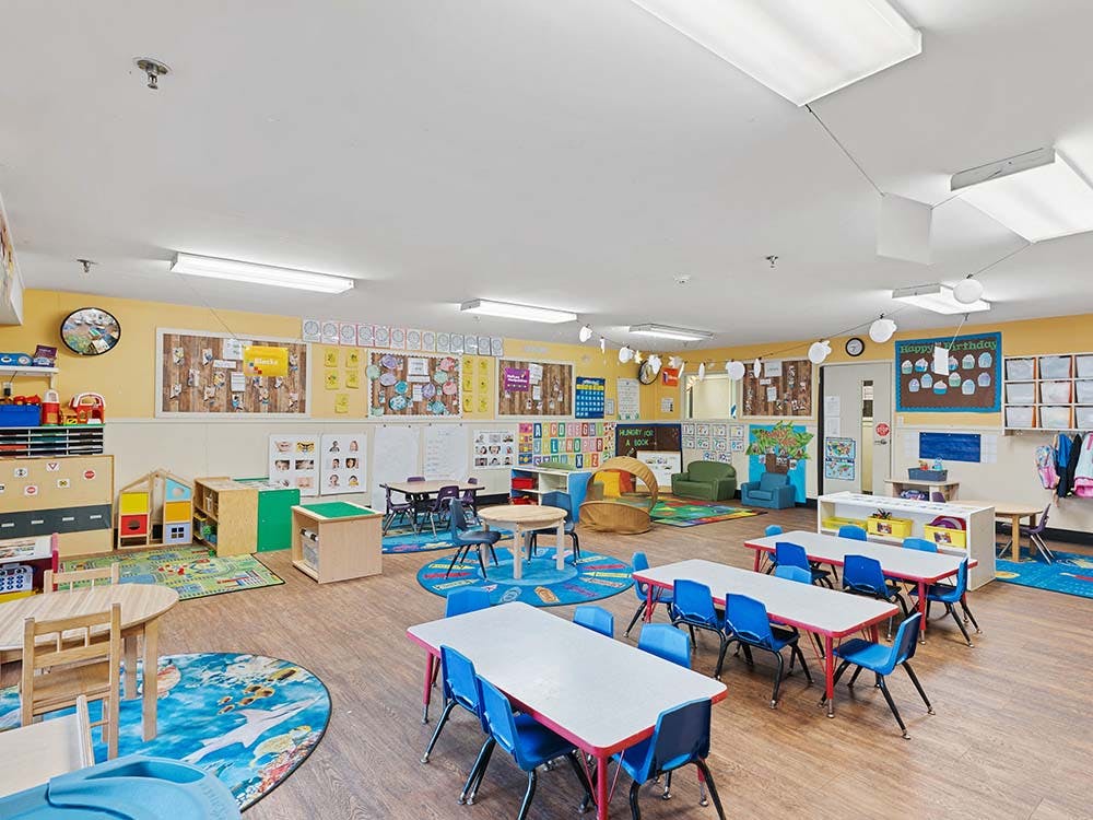 Empty colorful preschool classroom with tables and chairs