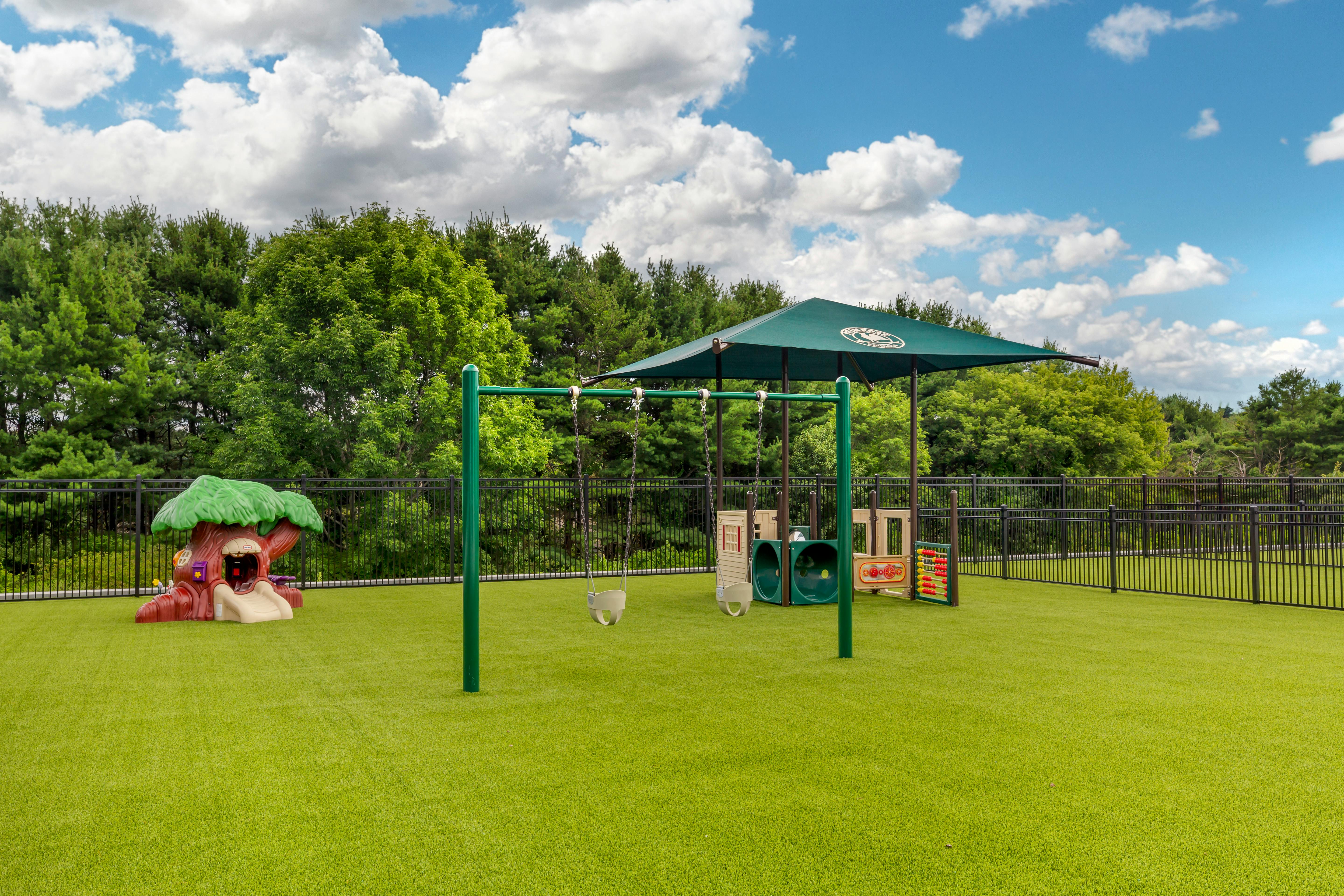 Playground with swings, a treehouse play structure, and a covered play area