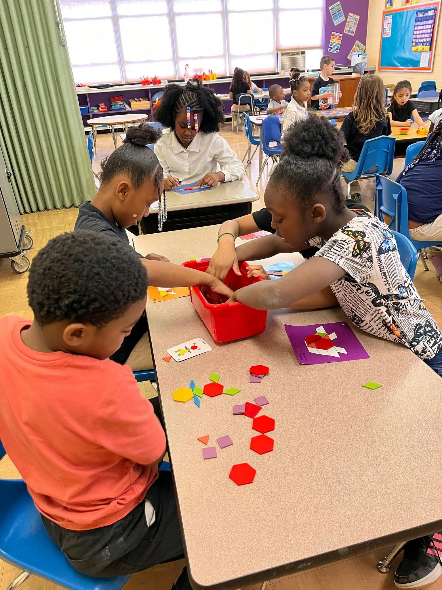 Children working with colorful geometric pattern blocks at a classroom table