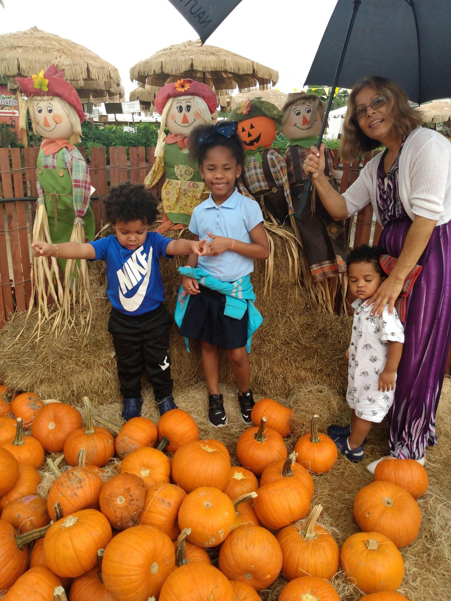 Adult and three children with pumpkins and scarecrows