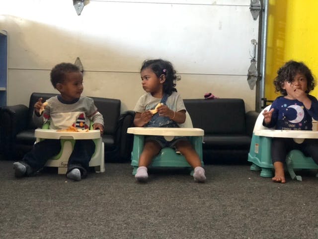 Three children sitting in high chairs