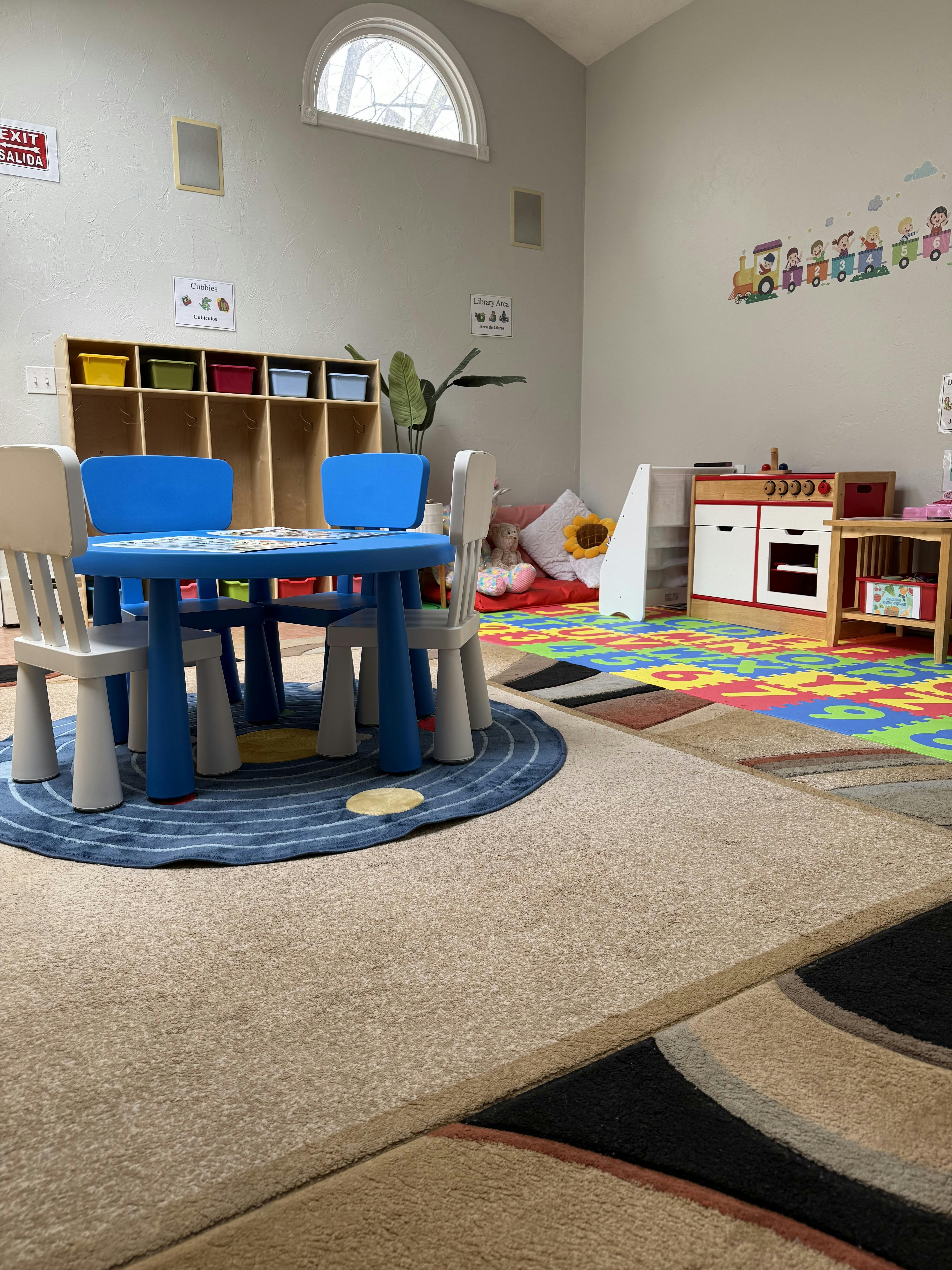 Children's play area with small blue table and chairs, shelves, and play kitchen