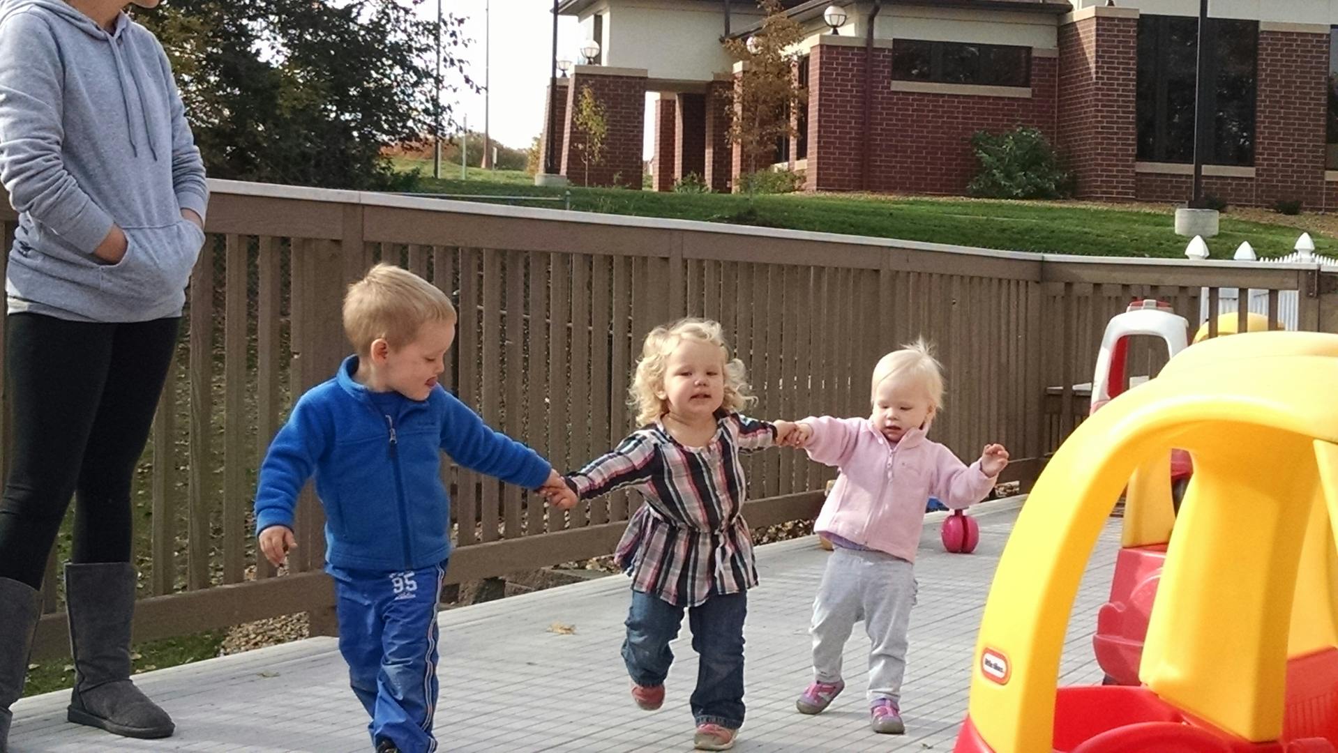 Person standing with three children holding hands and walking together