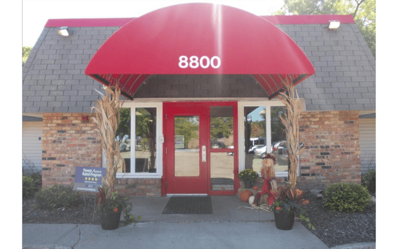 Entrance to a brick building with a red awning and the number 8800