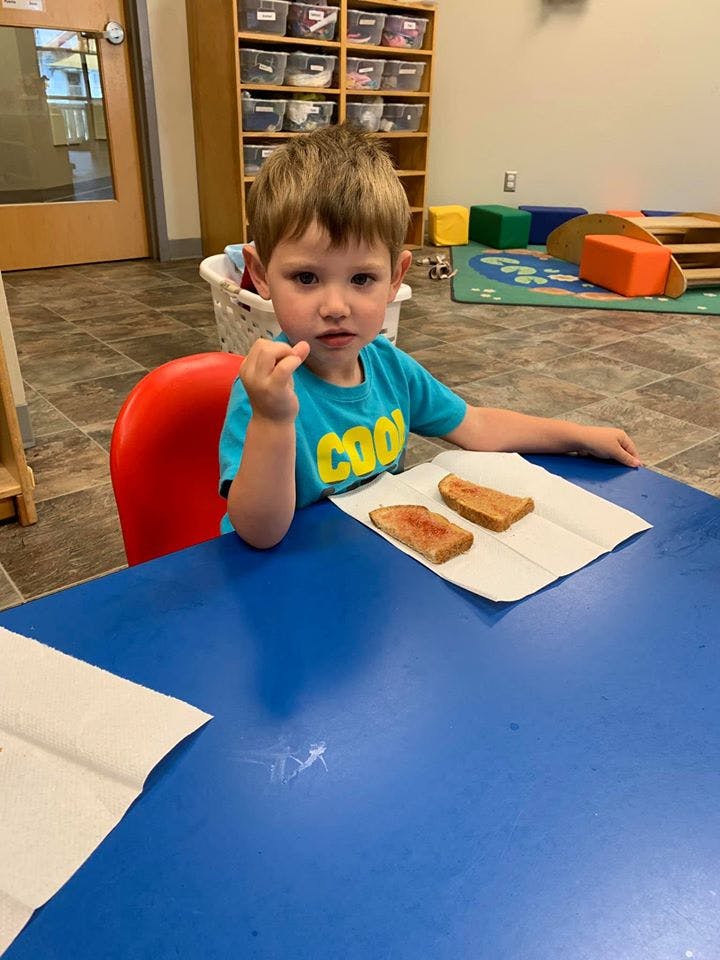 Child sitting at a table with two pieces of toast