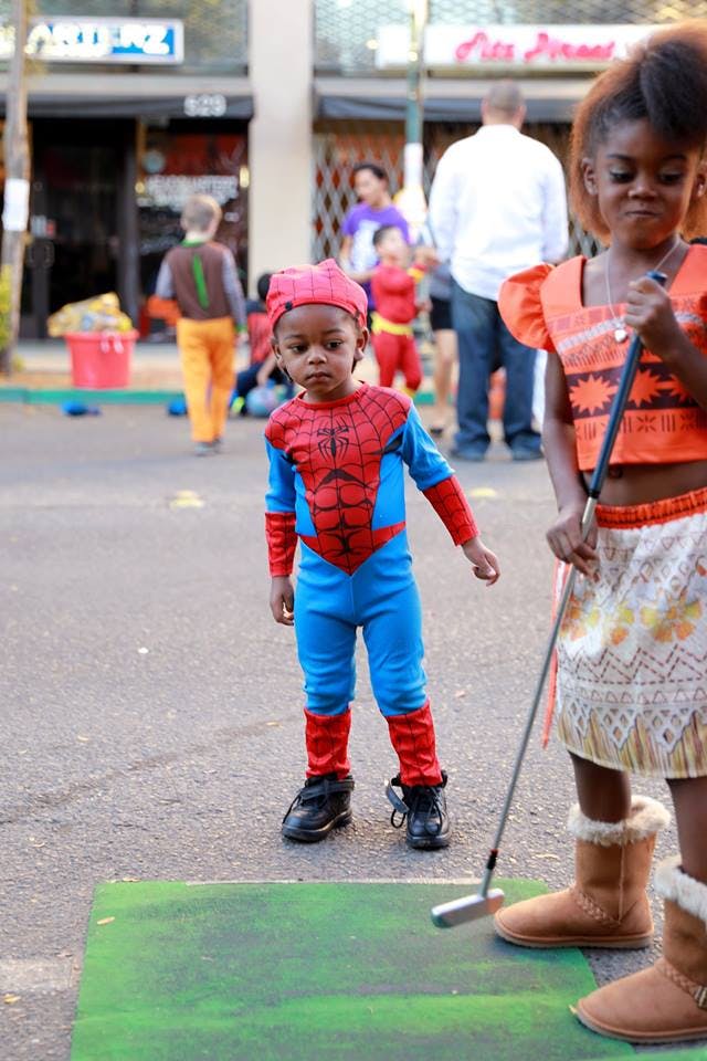 Child in Spider-Man costume standing next to another child holding a golf club